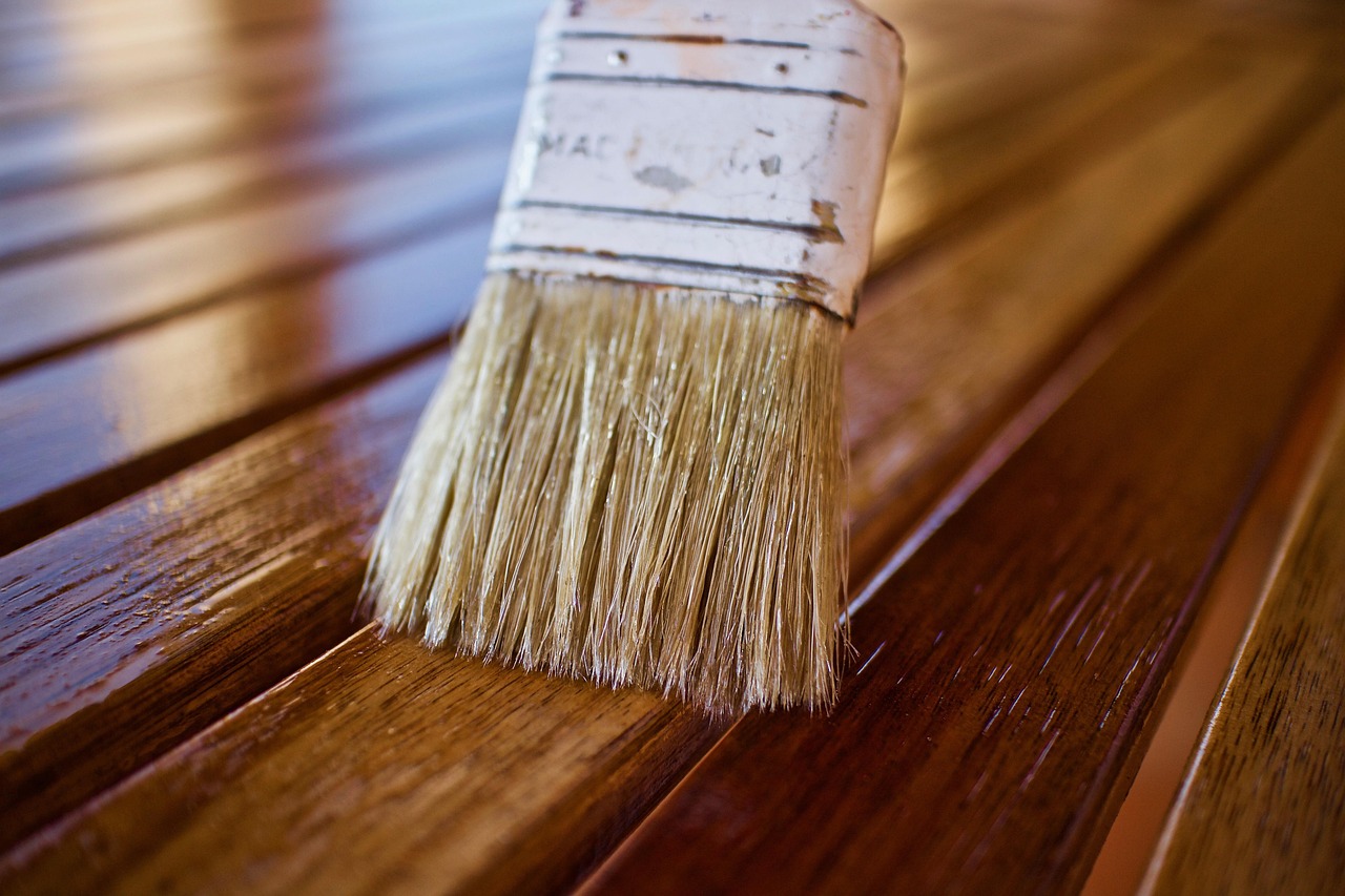 Brush applying wood stain on deck planks